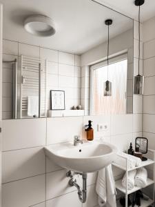 a white bathroom with a sink and a mirror at Urban Suite - Detmold in Detmold