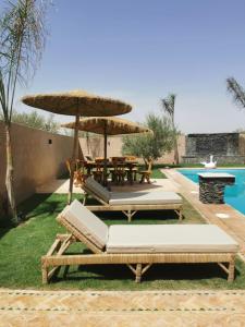 une terrasse avec une table, des chaises et un parasol dans l'établissement Villa Baraka, à Marrakech