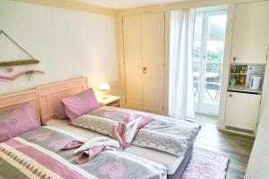 um pequeno quarto com uma cama com lençóis cor-de-rosa e brancos em Doppelroom with Terrace em Därligen