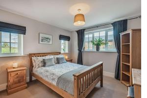 a bedroom with a bed and two windows at Pheasant Cottage in Tarporley