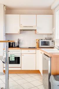 a white kitchen with white cabinets and appliances at T2 Massy Vilmorin 3 min Gare RER TGV in Massy