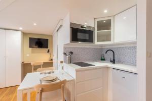 een keuken met witte kasten en een tafel en stoelen bij Charming renovated and bright studio in the center in Lille