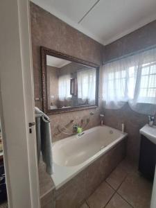 ein Badezimmer mit einer großen Badewanne und einem Spiegel in der Unterkunft Ukuthula Blissful Breakaways in Margate