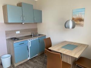 a kitchen with blue cabinets and a table with chairs at Küstenbrise 1 in Graal-Müritz