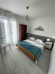 a bedroom with a large bed and a chair at Maison 6 personnes Soulac Climatisée Fibre in Soulac-sur-Mer