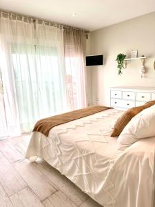 un grande letto bianco in una camera da letto con finestre di CASA RURAL AREV a Herrera del Duque