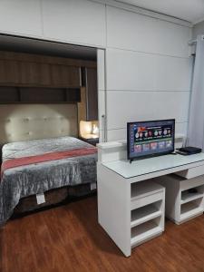 a bedroom with a bed and a desk with a television at Hotel Av Ibirapuera 2534 Moema São Paulo 3 in São Paulo
