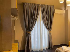 a window with curtains in a bedroom at Hotel Lukas in Viareggio