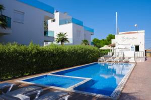 a swimming pool with chairs next to a building at Acrotel Porto Brava Luxury Villas in Ormos Panagias