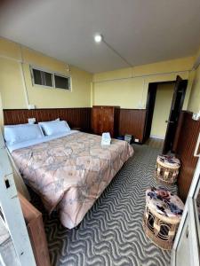 1 dormitorio con 1 cama grande y 2 taburetes en Seven Pines, en Darjeeling