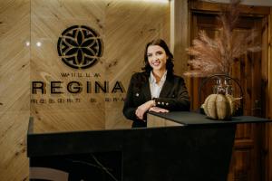 une femme debout à une table devant un panneau dans l'établissement Willa Regina II Resort & SPA, à Zakopane