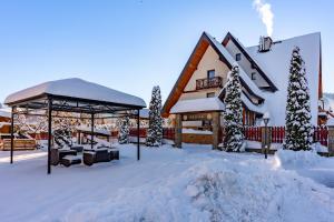 un bâtiment avec un kiosque dans la neige dans l'établissement Willa Regina II Resort & SPA, à Zakopane