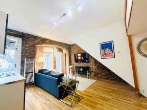 a living room with a blue couch and a brick wall at Highgate Garden Apartment- 2 Bed in London