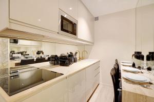 uma cozinha com armários brancos e uma mesa com cadeiras em Rénovation Chic Appart 17th Terrace & Mezzanine em Paris