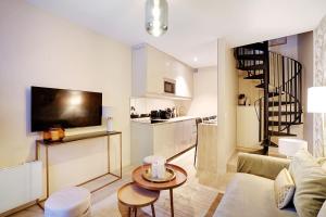 ein Wohnzimmer mit einem Sofa und einem Tisch sowie eine Küche in der Unterkunft Rénovation Chic Appart 17th Terrace & Mezzanine in Paris