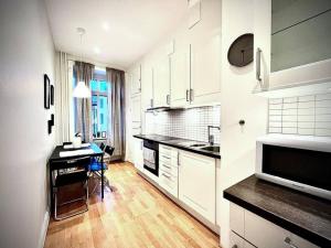 uma cozinha com armários brancos, uma mesa e um micro-ondas em Luxury Apartment In City Centre em Gotemburgo