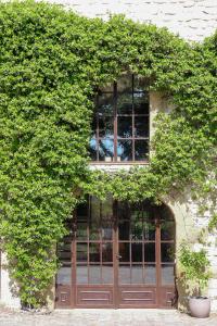 um edifício coberto de hera com uma porta e janelas em Domaine du Moulin de Villefranche em Pernes-les-Fontaines