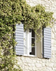 una ventana con persianas blancas en un edificio de piedra en Domaine du Moulin de Villefranche en Pernes-les-Fontaines