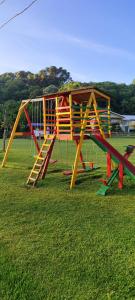 a wooden play structure in a field of grass at Cabanas Loft Paraíso in Gramado