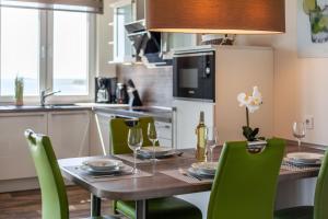 a kitchen with a wooden table and green chairs at mit Meerblick und Balkon, gratis Nutzung vom AHOI Erlebnisbad und Sauna in Sellin - Meeresblick FeWo 70 in Göhren