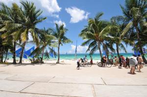 a group of people on a beach with palm trees at Astoria Current in Boracay