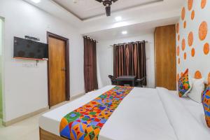 - une chambre avec un grand lit et une télévision murale dans l'établissement FabExpress Abode Inn, à New Delhi