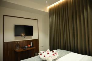 a bedroom with a television and a bed with flowers on it at Mango Leaf Lake Resort in Pune