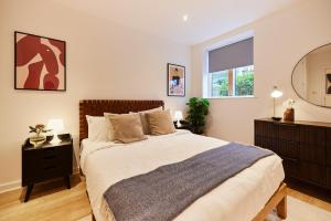 1 dormitorio con 1 cama grande y espejo en The Putney Escape - Trendy 2BDR Flat with Terrace + Parking en Londres