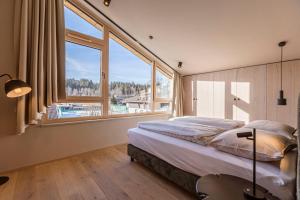 a bedroom with a large bed and large windows at Kitzbühel Suites by ALPS RESORTS in Oberndorf in Tirol +74 photos