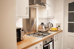 a kitchen with a stove top oven next to a microwave at Well decorated 2 bed home in Handbridge, Chester in Hough Green