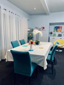 mesa de comedor con sillas azules y mantel blanco en Kelvin Garden Villa en Queenstown