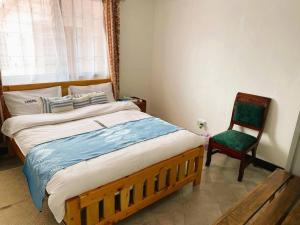 een slaapkamer met een groot bed en een stoel bij 3 Bedroom Laneens Nest in Nakuru