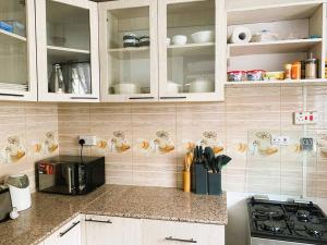 een keuken met witte kasten en een zwarte magnetron bij 3 Bedroom Laneens Nest in Nakuru