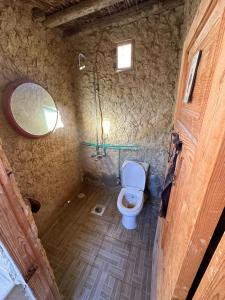 a bathroom with a toilet and a mirror in it at Muhra Camp Siwa in Siwa
