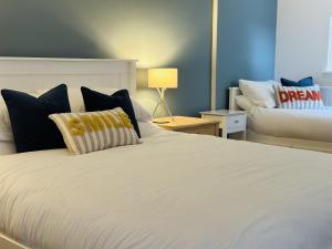 a bedroom with a large white bed with pillows at Bromholme Cottage Bacton - Sleeps 10, hot tub, close to beach in Bacton