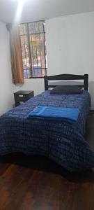 1 dormitorio con 1 cama con edredón azul y ventana en Departamento Completo Zona residencial la Molina, en Lima