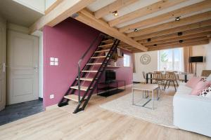 a living room with a pink wall and a spiral staircase at Appartement 2 chambres de caractère. in La Madeleine
