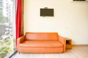 un sofá naranja sentado en una habitación con TV en FabHotel Cozy Inn en Bombay