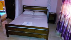 un letto con lenzuola bianche e 2 cuscini sopra di Checkpoint Inn Hotel, Mombasa a Mombasa