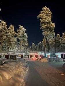 a snow covered street with houses and trees at night at Ekokatti Cottages in Vuokatti