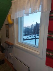 a window with a view of a snow covered street at 120 yrs. old log house in Kuopio city centre in Kuopio
