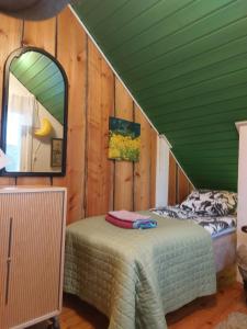 a bedroom with a green ceiling with a bed and a mirror at 120 yrs. old log house in Kuopio city centre in Kuopio