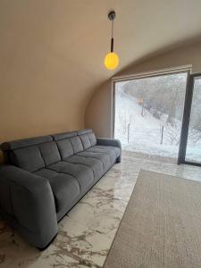 un divano in soggiorno con una grande finestra di Apple Resort a Almaty