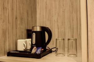 eine Kaffeemaschine auf einer Theke mit zwei Gläsern in der Unterkunft HOTEL 16 AVENUE in Kalkutta