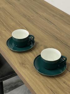 dos tazas y platillos sentados en una mesa de madera en Aparan Hotel, en Aparan