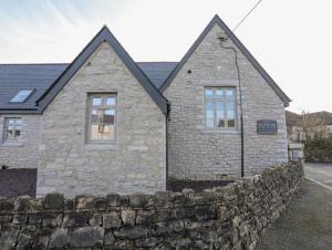 a stone house with a stone wall in front of it at Ysgol Fawr Big School in Brynteg