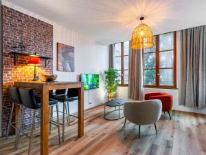 uma sala de estar com uma mesa e cadeiras e uma parede de tijolos em Le Relais DUCAL - Appartements d'Hôtes Vieille Ville em Nancy