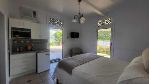 a white bedroom with a bed and a kitchen at Ribbonwood Bed & Breakfast, Emu Park Qld in Emu Park