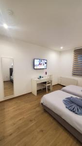 1 dormitorio con 2 camas, escritorio y TV en TOUCH DOWN Motel en Lohmar
