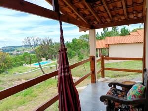 a hammock on a porch with a view of a pool at Toca dos Coelhos Chalés in Carrancas